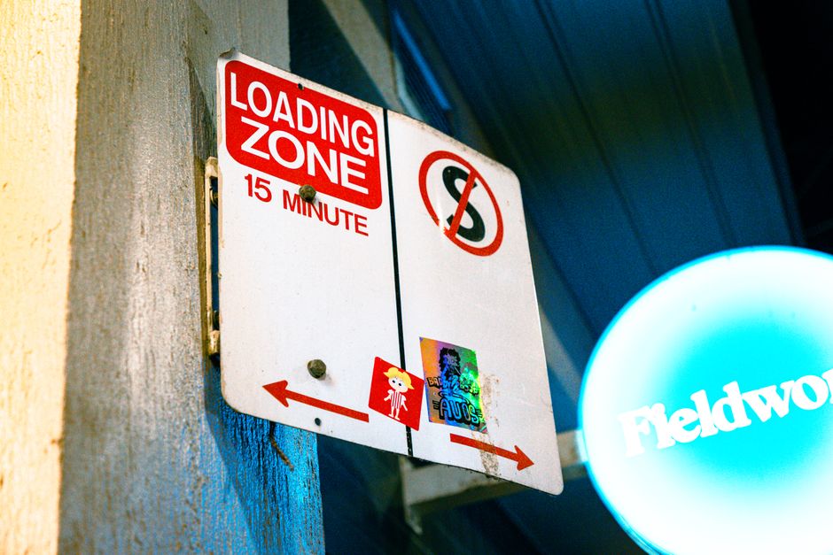 Close-up image of a rectangular sign attached to a metallic garage door or loading area entrance. The sign displays the text 'PRIVATE PROPERTY LOADING ZONE ONLY' in bold black letters on a white backg